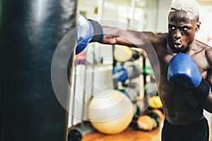 Young black man boxing inside training fitness gym club - African fit boxer doing workout session - Sport, self defense and