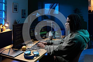 Young Black Man Coding Software on Multiple Computer Monitors at Night