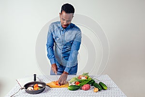Young black man cooking at home domestic kitchen and preparing a vegetarian meal.vegan food on white background in