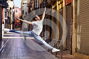 Young black man doing an acrobatic jump in the middle of the street.