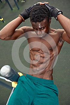 Young black man doing crunches outdoors. He is in a park.
