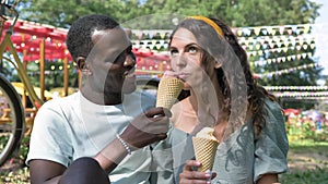 Young black man gives brunette woman ice-cream to taste