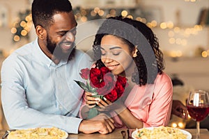 Young black man giving flowers to woman