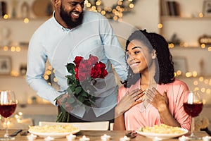Young black man giving red roses to woman