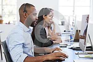 Young black man with headset working at computer in office