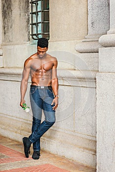 Young black man holding white rose, standing outdoors in New York City, looking down, thinking