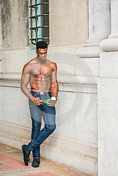 Young black man holding white rose, standing outdoors in New York City, looking down, thinking