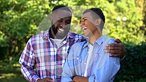 Young black man hugging younger brother laughing having fun together, family