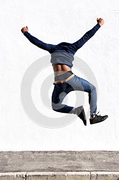 Young black man jumping in air on sidewalk outdoors