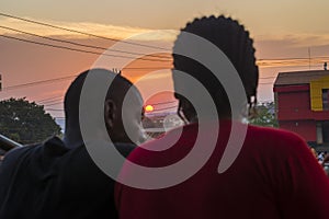 young black man and lady sitting together outside having a conversation while the sun sets