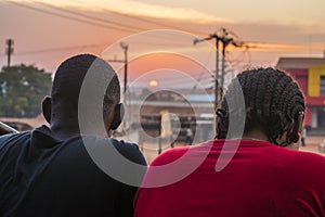 young black man and lady sitting together outside having a conversation and watching the evening sunset