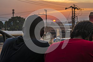 young black man and lady sitting together outside having a conversation and watching the evening sunset