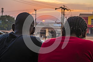 young black man and lady sitting together outside having a conversation and watching the evening sunset