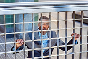 Young black man looking out throung fence in New York City