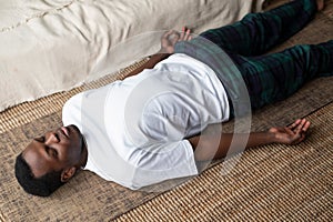 Young black man lying in Dead Body exercise or Corpse pose with his eyes closed, Savasana pose