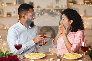 Young black man making proposal with ring to his woman