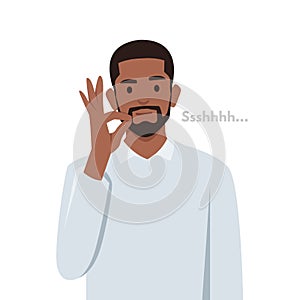 Young black man making a shushing gesture raising his finger to his lips photo
