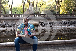 A young black man in park. Outdoor portrait of traveler. Portrait of a young african man outdoors. Outdoors portrait concept