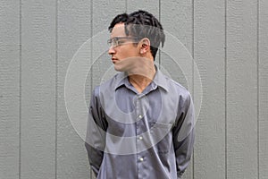 Young black man in profile, collared shirt with hands behind back, pensive look, natural black hair in twists