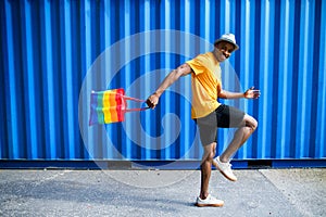 Young black man with rainbow bag walking, black lives matter concept.