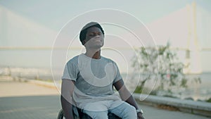 Young Black man riding in wheelchair along seashore.