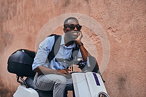 Young black man on scooter with mobile phone