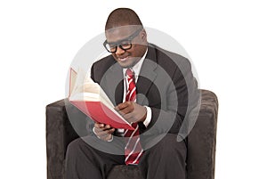 Young black man sitting in chair reading a book