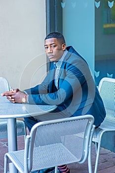 Young black man sitting outdoors in New York City, relaxing, thinking