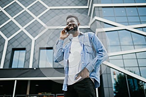 Young black african man smiling and talking on mobile phone outside