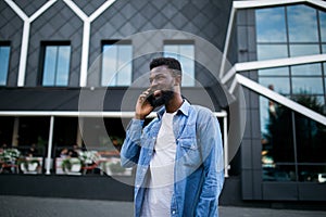 Young black african man smiling and talking on mobile phone outside