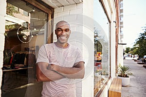 Young black man smiling to camera outside his clothes shop