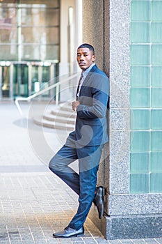 Young black man standing outdoors against wall in New York City, relaxing