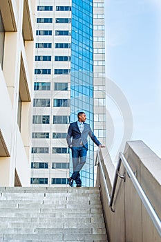 Young black man standing outside office building in New York City, looking forward