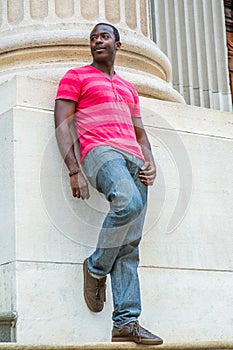 Young black man standing outside office building in New York City, relaxing