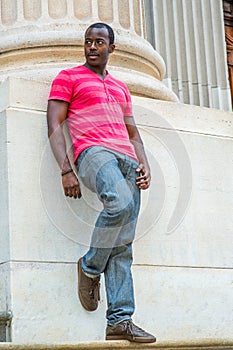 Young black man standing outside office building in New York City, relaxing