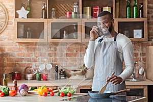 Young black man talking on mobile phone in kitchen