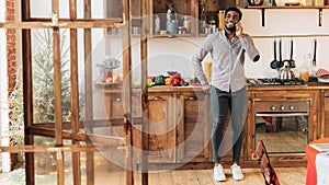 Young black man talking on mobile phone in kitchen