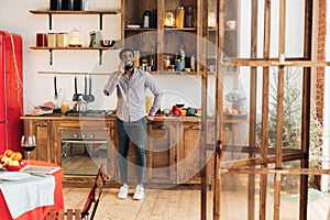 Young black man talking on mobile phone in kitchen