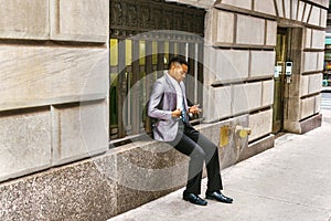 Young black Man texting on cell phone on street in New York City