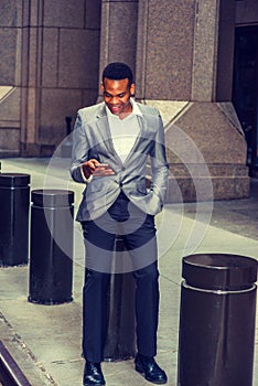 Young black man texting on cell phone on street in New York City