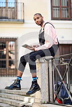 Young black man using digital tablet in urban background.