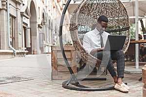 Young black man using a laptop computer outside a cafe