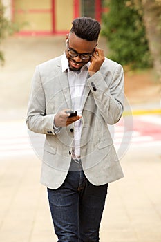 Young black man walking outside and listening to music with earphones