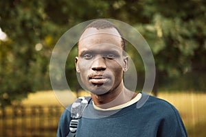 A young black man is walking in the park. Close up portrait.