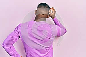 Young black man wearing casual pink sweater backwards thinking about doubt with hand on head