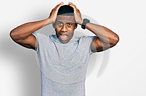 Young black man wearing casual t shirt crazy and scared with hands on head, afraid and surprised of shock with open mouth