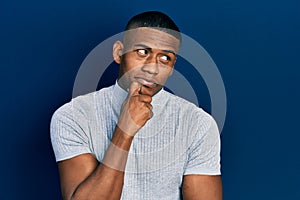 Young black man wearing casual t shirt serious face thinking about question with hand on chin, thoughtful about confusing idea