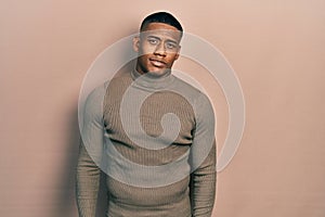 Young black man wearing casual turtleneck sweater relaxed with serious expression on face