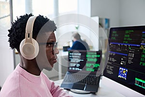 Young Black Man Wearing Headphones Working on Computer Programming Code
