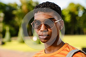 Young black man wearing piercing and sunglasses walking in park